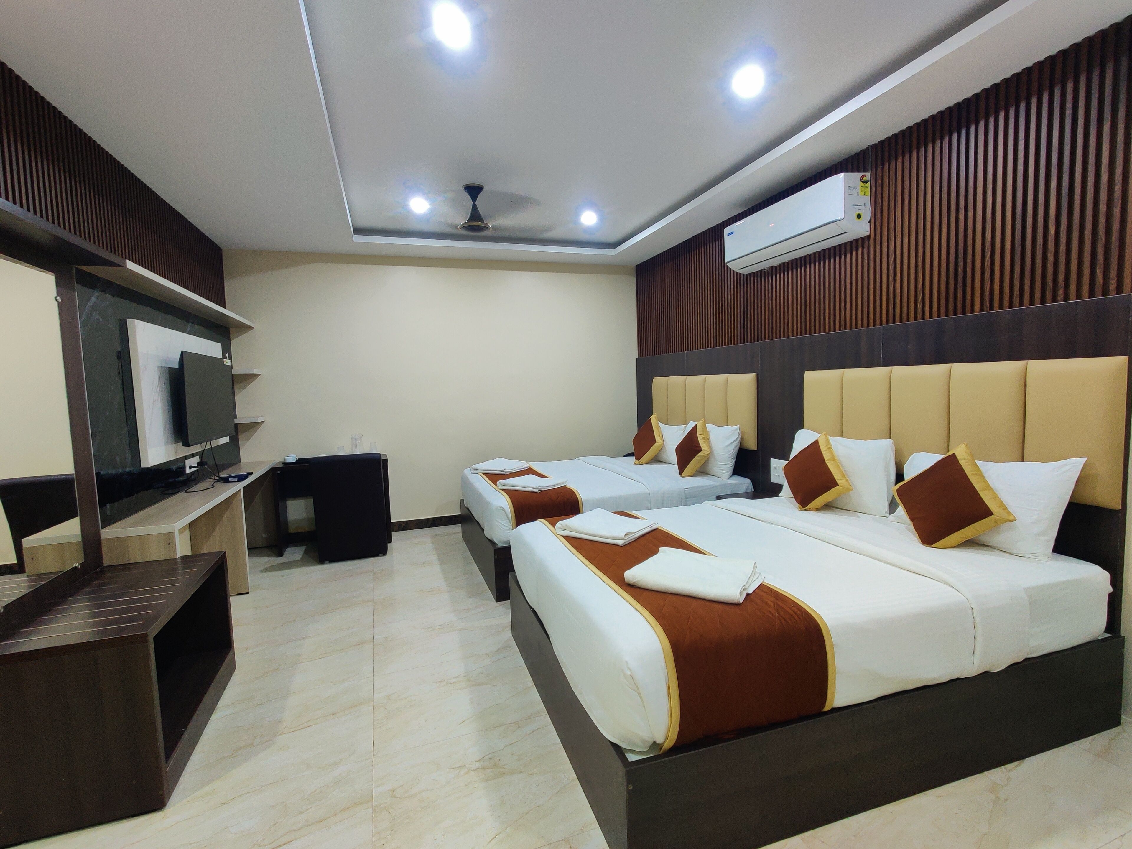 Una habitación de hotel con una cama grande, televisión, escritorio y ventilador de techo.