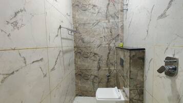 Un baño con paredes de mármol, ducha e inodoro.