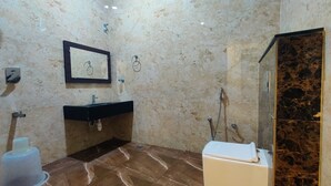 Ein Badezimmer mit Marmorboden, Waschbecken, Spiegel, Handtuchhalter und Duschbereich.