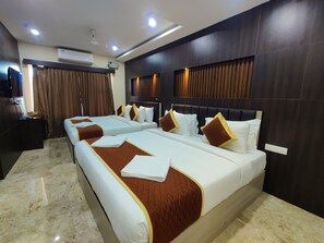 A hotel room with two beds, a flat-screen TV, an air conditioning unit, and a ceiling fan.