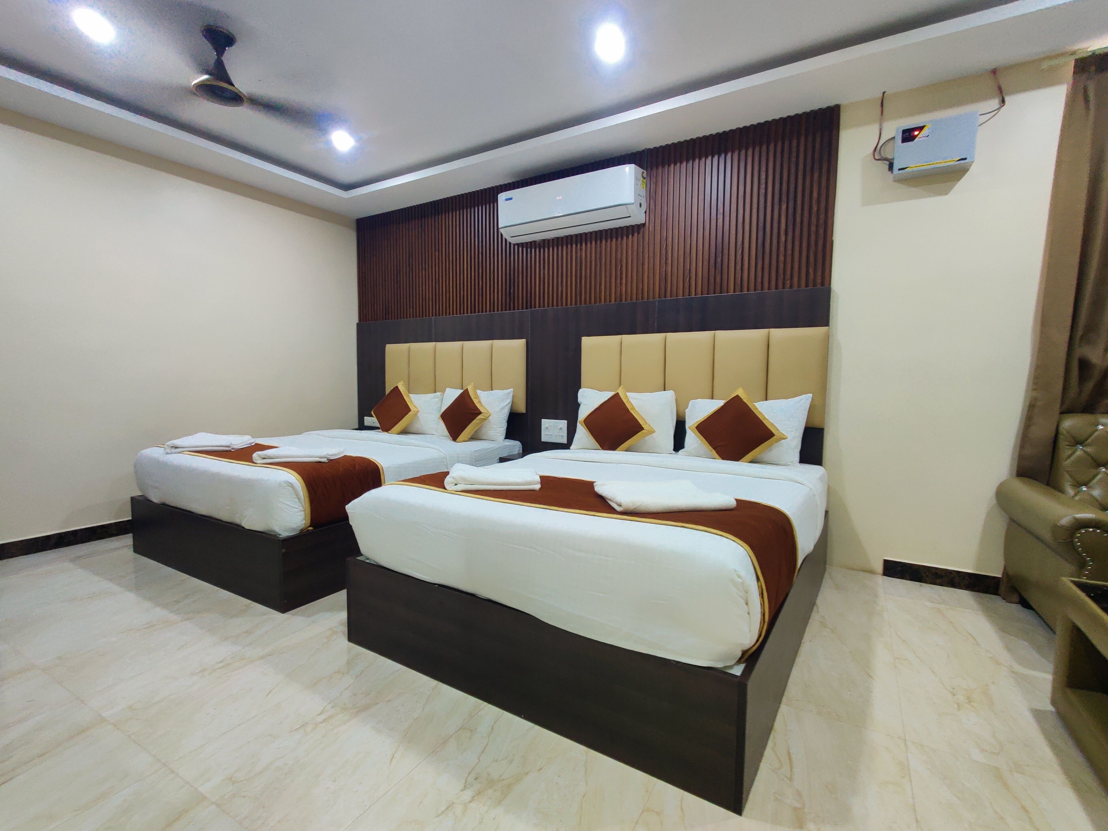 A hotel room with two beds, an air conditioning unit, and a ceiling fan.