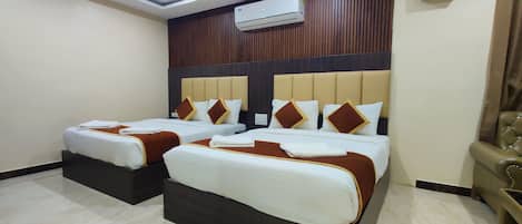 A hotel room with two beds, an air conditioning unit, and a ceiling fan.