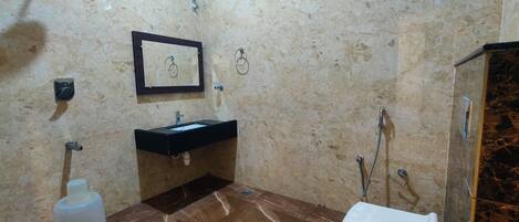 Un baño con piso de mármol, lavamanos, espejo y ducha.