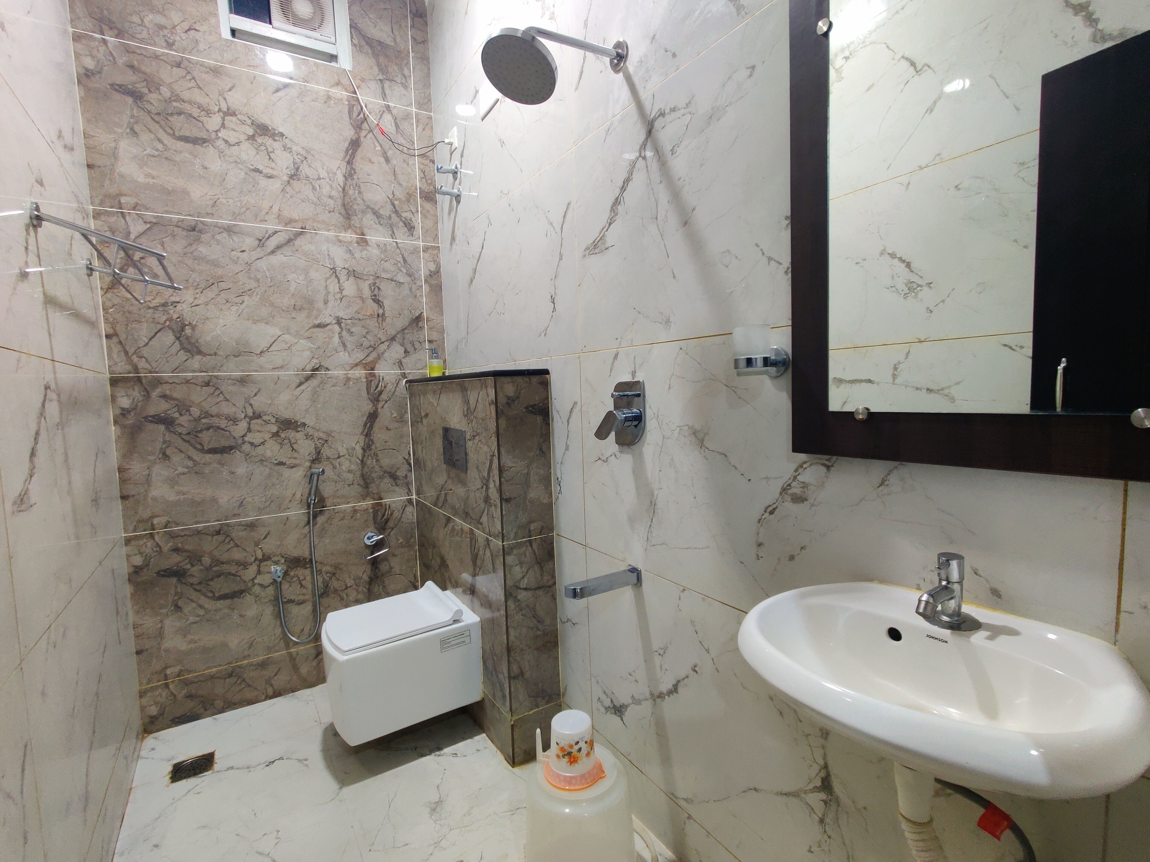 Un baño con lavamanos blanco, un espejo, ducha e inodoro.