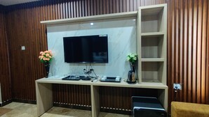 Ein modernes Wohnzimmer mit integriertem Fernseher, Holzpaneelwänden, einem Marmorboden und einem Sofa.