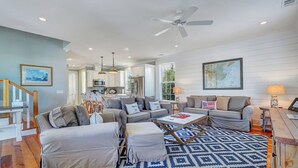 A spacious living room with a large sofa set, a coffee table, and a patterned rug. - Coastal Chic Home w/ Multiple Decks, Steps to Beach + River by Tybee Cottages (Tybee Island)