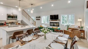 A spacious kitchen with a central island, a dining area with a table set for four, and a living area with a sofa and TV. - Near Rivers & Boating: Home w/ Hot Tub in Longview (Longview)