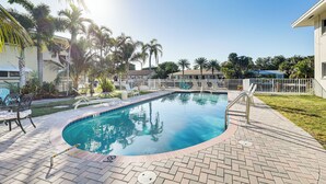A swimming pool with a tiled edge, surrounded by a brick patio, palm trees, and lounge chairs. - Waterfront Condo w/ Dock in Fort Lauderdale! (Fort Lauderdale)