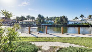 A waterfront property with a dock, a grassy area, and palm trees. - Waterfront Condo w/ Dock in Fort Lauderdale! (Fort Lauderdale)
