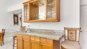 A kitchen with wooden cabinets, a granite countertop, and a bar stool. - Waterfront Condo w/ Dock in Fort Lauderdale! (Fort Lauderdale)