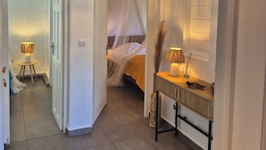A hotel room with a bed, bedside table, lamp, and a hanging light fixture. - Villa Cannelle Pointe Batterie, sea view, pool, 3 bedrooms (DESHAIES)
