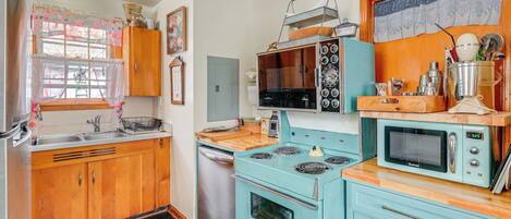 Una cocina con armarios de madera, estufa, microondas y pileta.