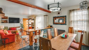 Un salón espacioso con una mesa de comedor de madera, un sofá rojo y un televisor montado en la pared.