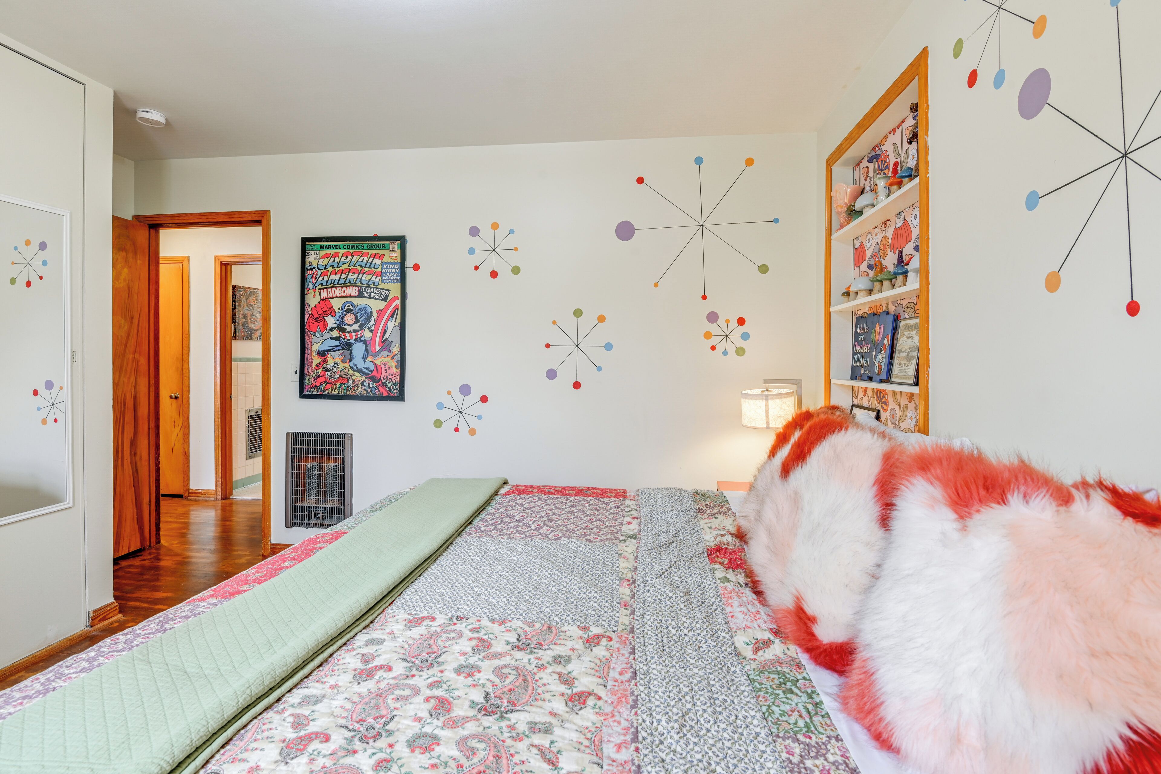 A bedroom with a bed, a wall clock, a poster, and a bookshelf.