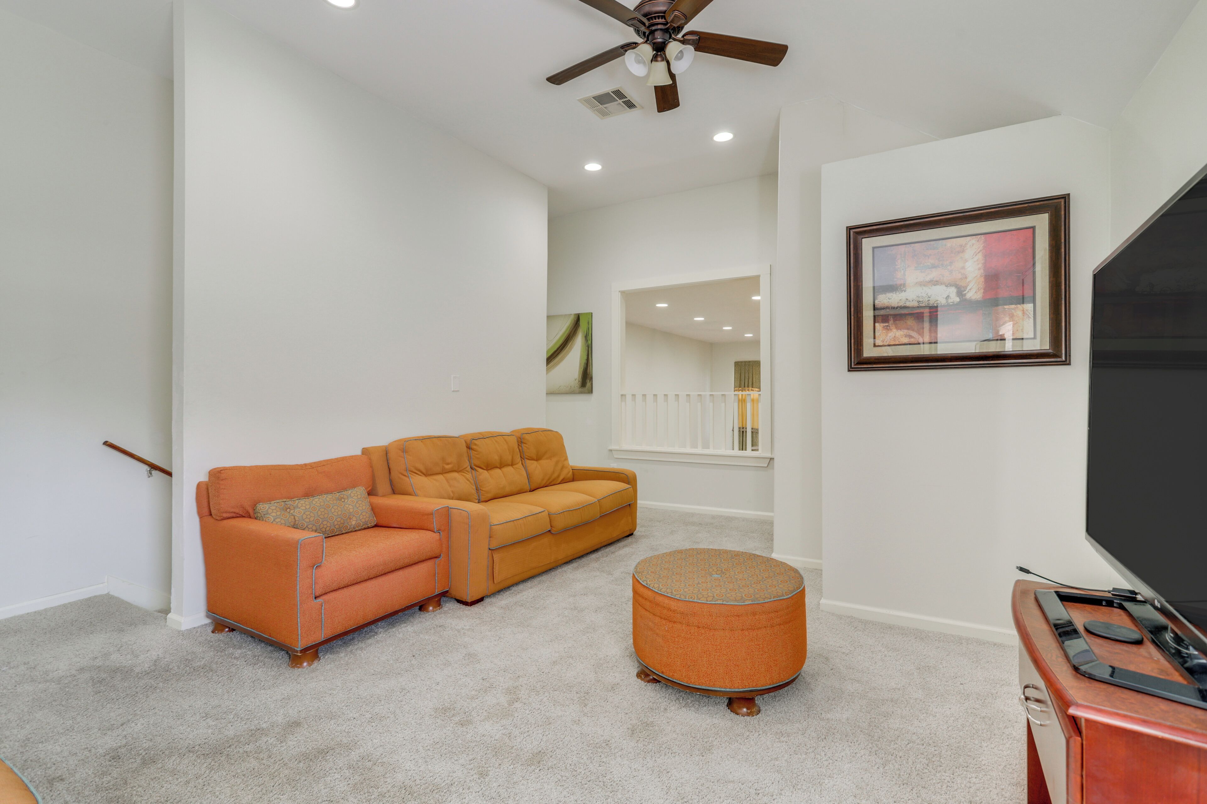 A living room with a sofa, ottoman, and a TV stand.