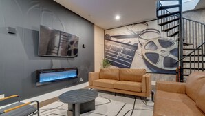 Una sala de estar moderna con una televisión de pantalla plana, un sofá, una mesa de centro y una escalera.
