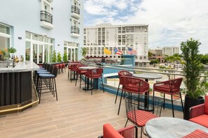 Un bar en la azotea con terraza, piscina y banderas.