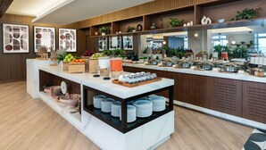 Una barra de desayuno moderna con una variedad de frutas, un dispensador de jugo y platos apilados con cuidado.