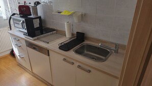 Une cuisine équipée d’un évier, d’une machine à café et d’un égouttoir à vaisselle.