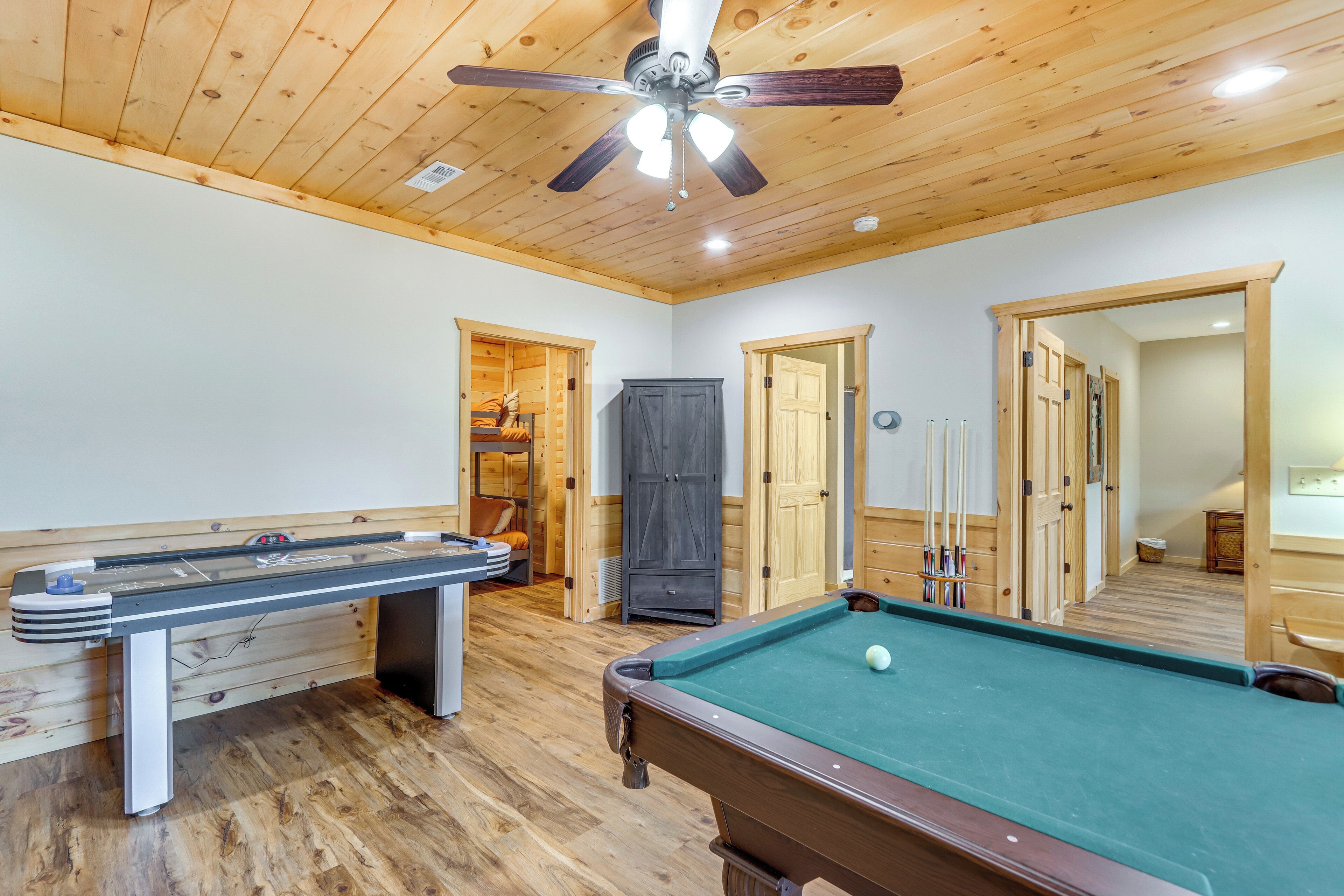 A pool table with a ceiling fan, wooden floors, and a door leading to a closet.