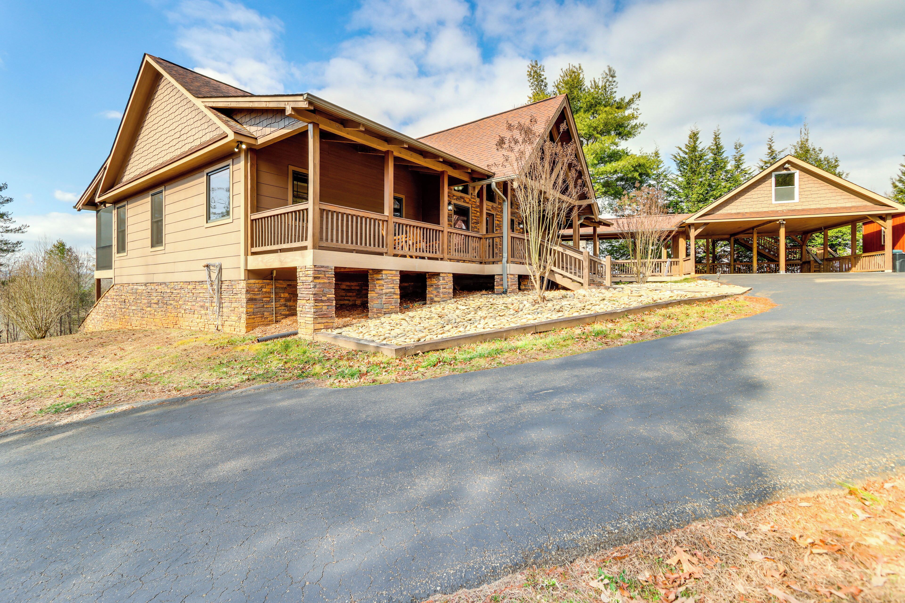 A large, two-story lodge with a covered front porch, stone foundation, and a driveway leading to the entrance.
