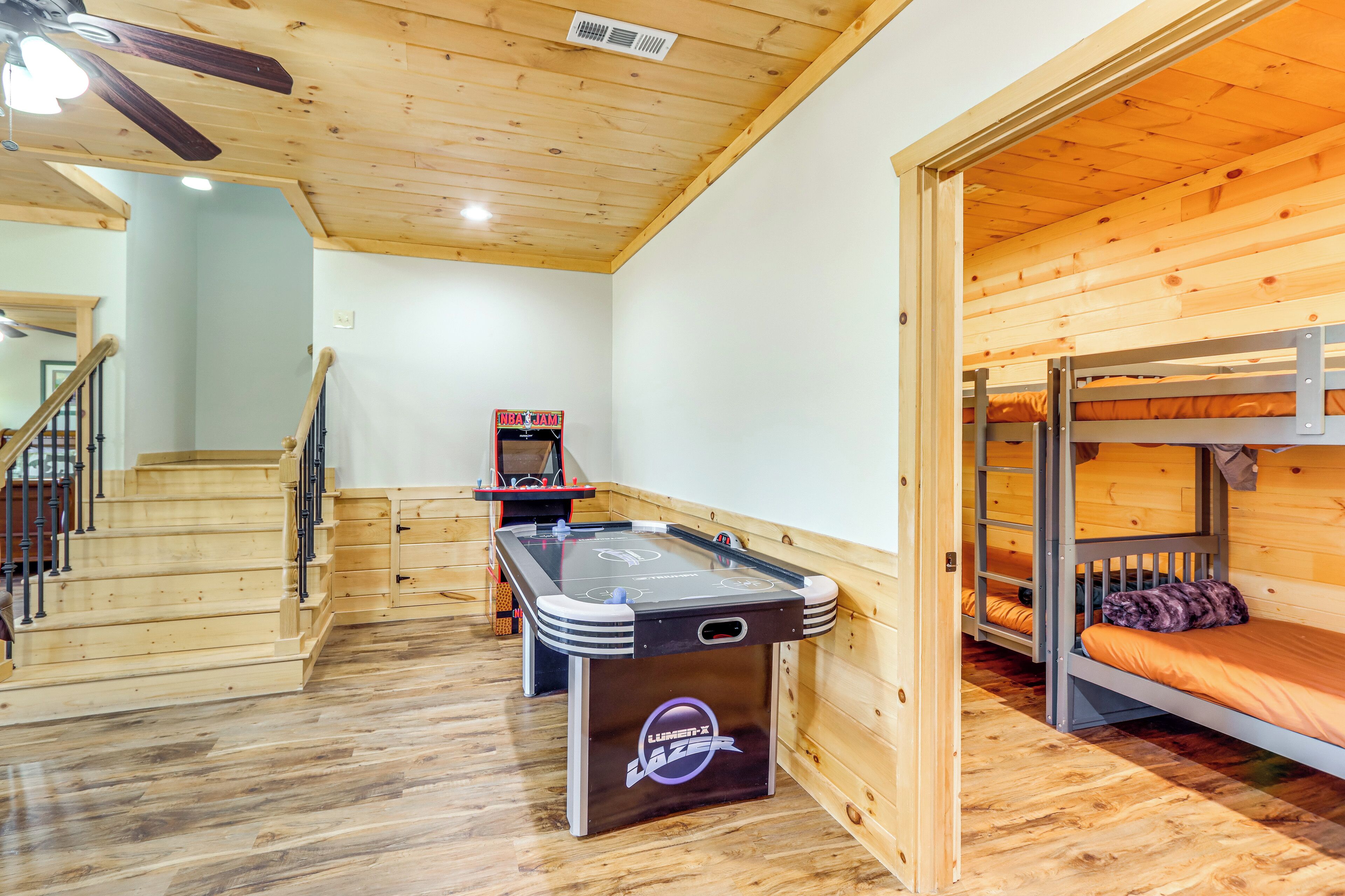 A room with a pool table, bunk beds, and a staircase.