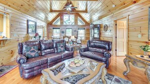 Ein Interieur einer Blockhütte mit zwei Ledersofas, einem Couchtisch und einem Deckenventilator.
