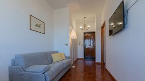 A hallway with a grey sofa, a floor lamp, a framed picture, and a mirror on the wall. - Casa Cecchi by Wonderful Italy (Torino)