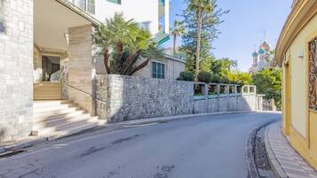 Una strada con un muro in pietra, una scala e un edificio con un balcone.