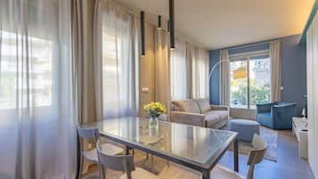 Un soggiorno moderno con tavolo da pranzo in vetro, divani grigi e una poltrona blu.