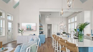 A spacious kitchen with a central island, white cabinetry, and a view of the beach through large windows. - New home in CS South with access to 20+ resort like amenities (Port Aransas)