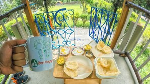 A dining table with food and a mug, surrounded by a metal railing and greenery. - Bon Holong Resort  (Alipurduar)