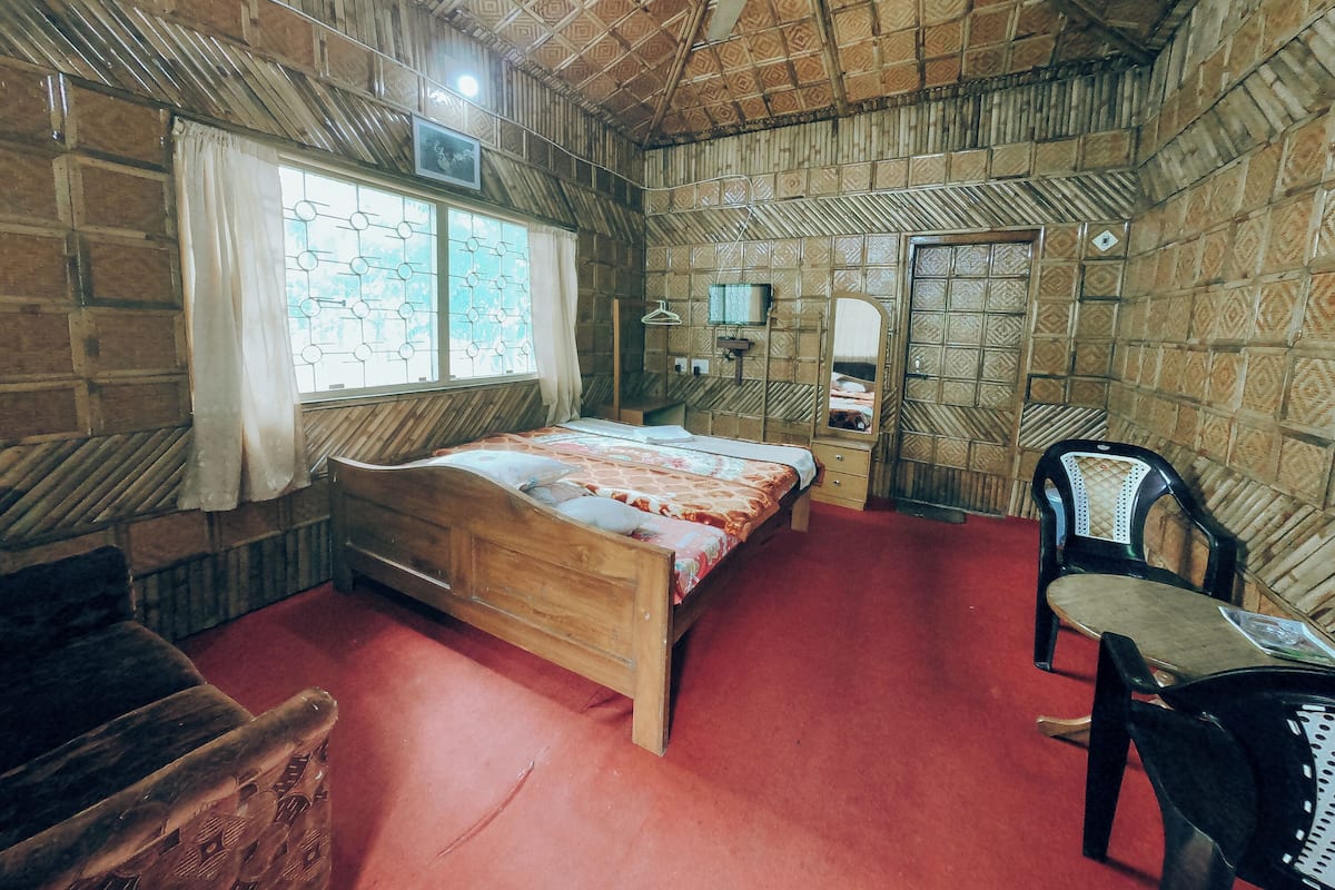 A room with a wooden bed, a desk, a chair, and a window with curtains.