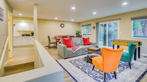 A spacious living room with a sofa, a coffee table, and a brightly colored chair. A dining area with a table and chairs is visible in the background.