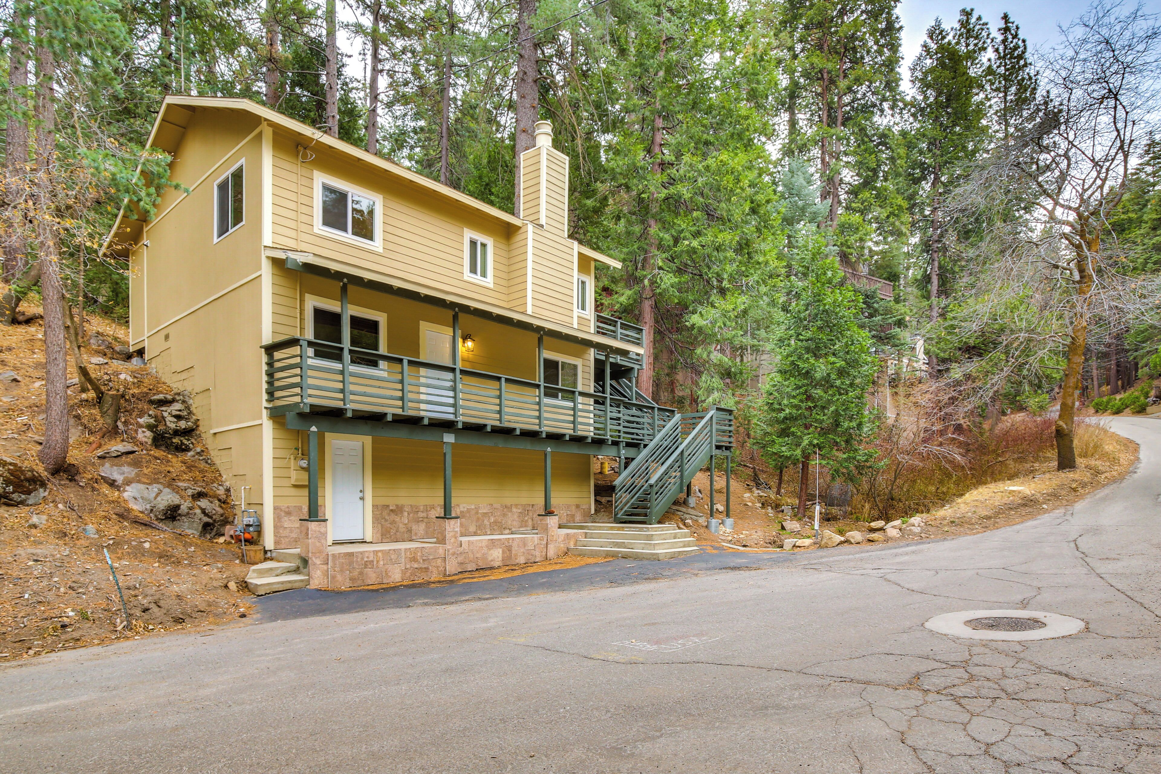 A two-story yellow house with a balcony and a staircase leading to the second floor.