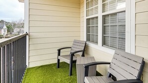 A balcony with two wooden chairs and a small patch of artificial grass. - 9 Mi to Dtwn Fayetteville: Condo w/ Pool Access! (Fayetteville)