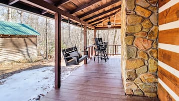 Relax in a serene outdoor space with a wooden deck, stone wall, and comfortable seating for two.