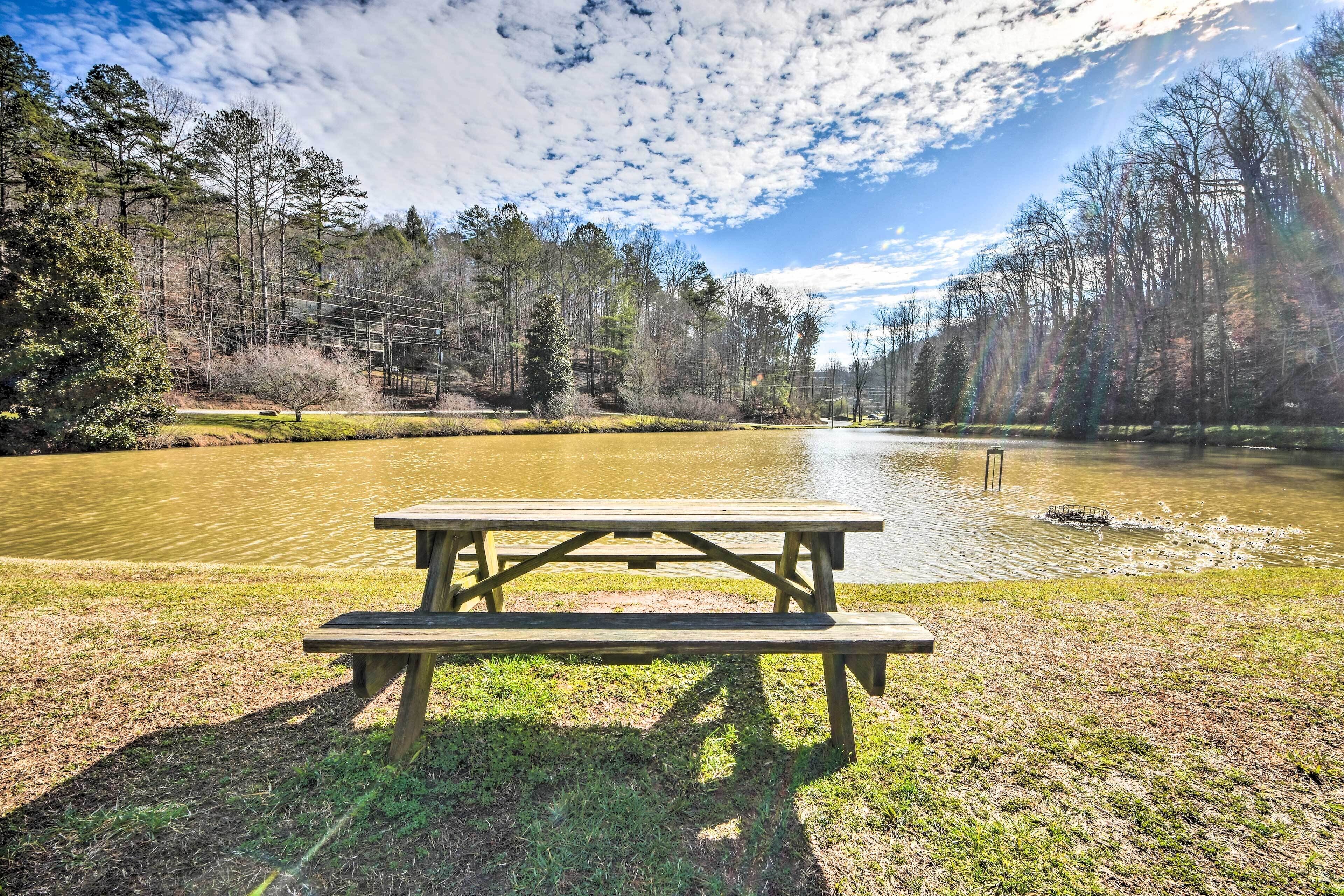 A picnic table by a calm lake surrounded by trees.