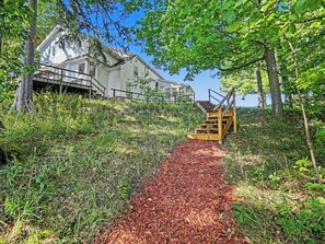 A wooden staircase leading to a house surrounded by trees and a path covered with red mulch. - Peaceful, Private Lakeside Home. Sleeps 16! (Pentwater)