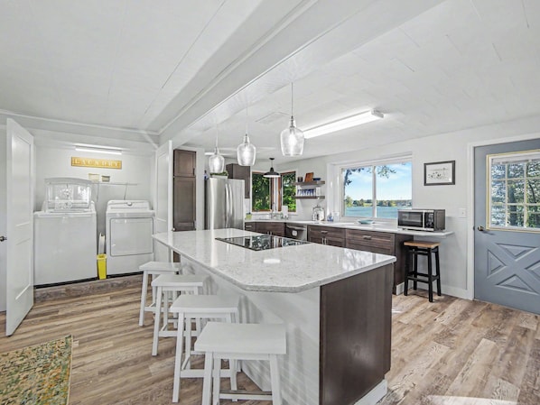 A modern kitchen with a large island, bar stools, and a view of the outdoors.