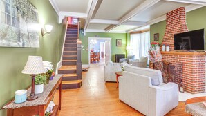 Ein geräumiges Wohnzimmer mit Kamin, einer Treppe und einem Essbereich im Hintergrund.