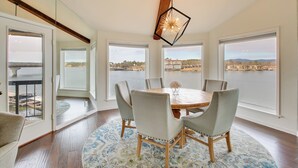 A dining area with a round table, six chairs, and a view of a body of water through large windows. - Million-dollar Views: Condo on Lake Hamilton! (Hot Springs)