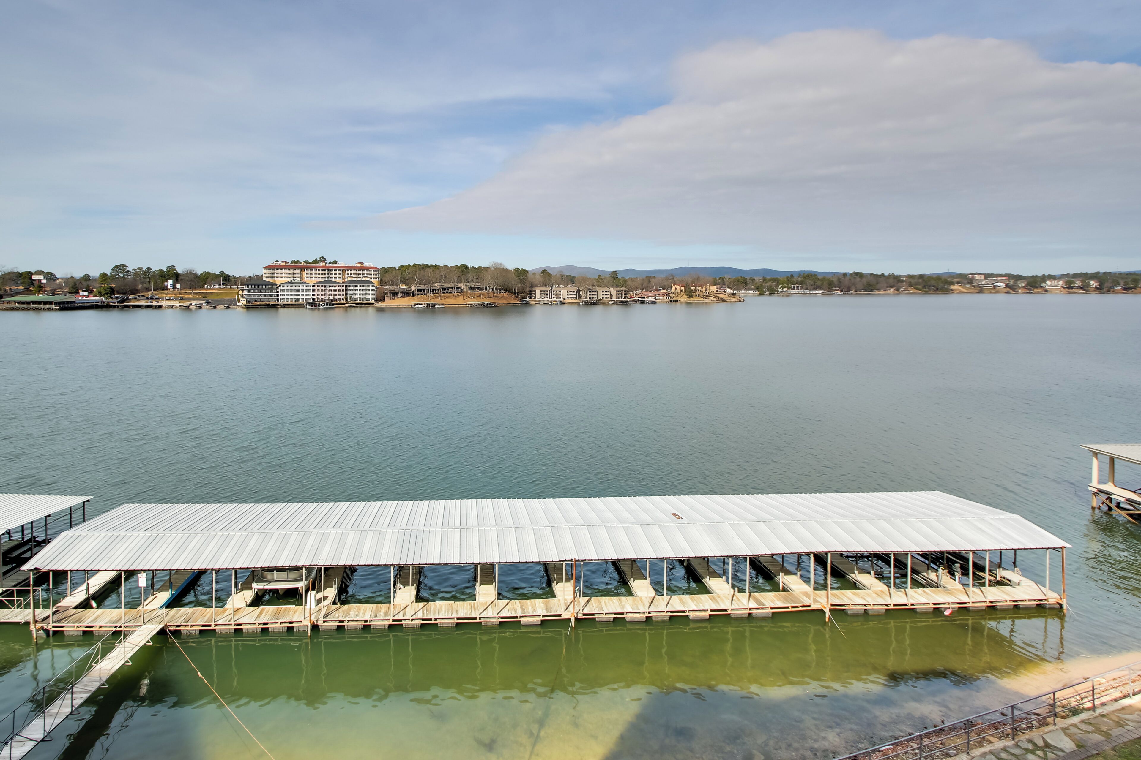 A waterfront dock with a covered seating area and a building in the background.