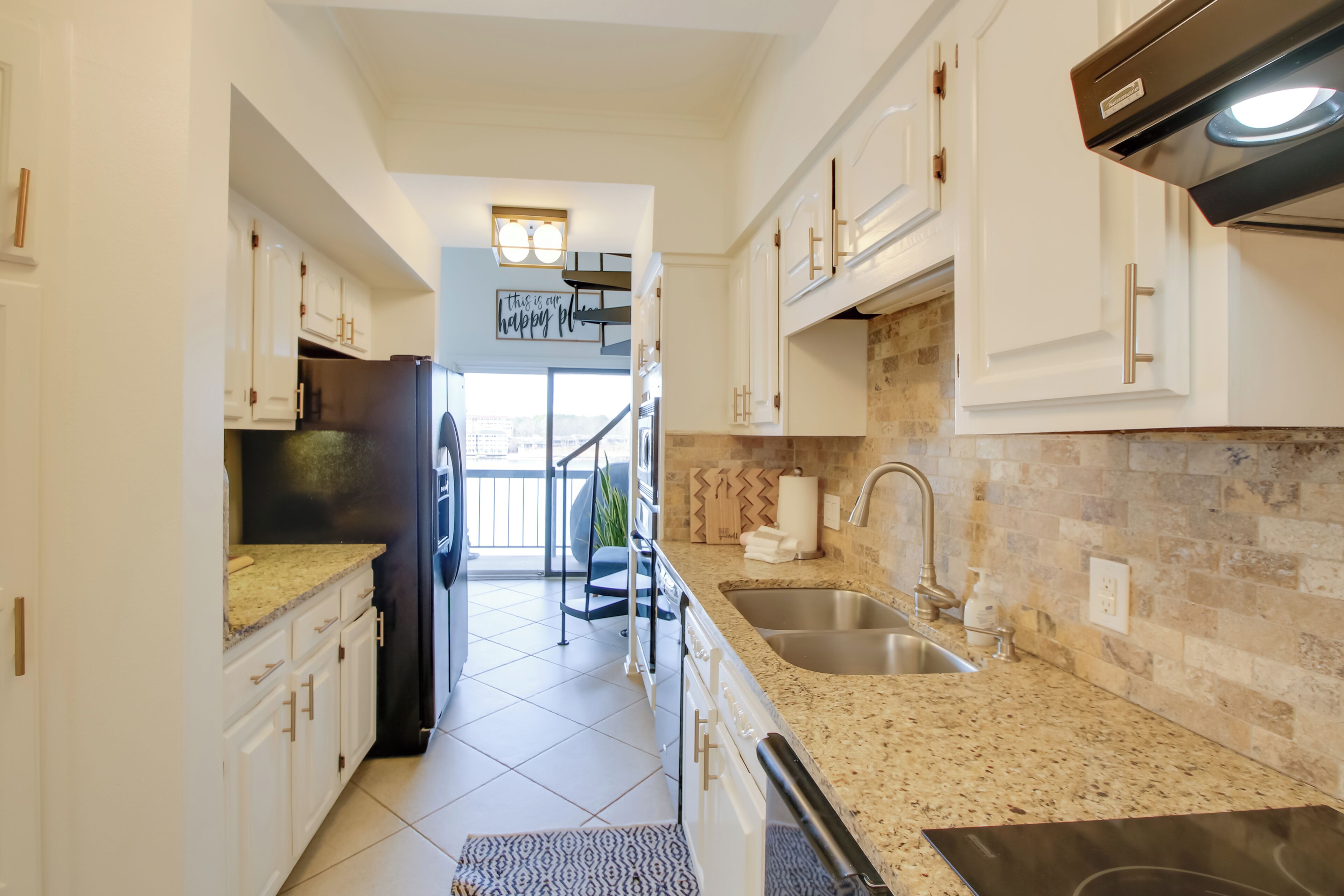 A modern kitchen with white cabinets, granite countertops, and stainless steel appliances.