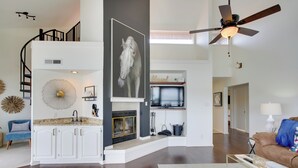 A spacious living area with a fireplace, a ceiling fan, and a large wall-mounted TV. - Million-dollar Views: Condo on Lake Hamilton! (Hot Springs)