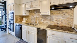 A modern kitchen with white cabinetry, a granite countertop, a brick backsplash, and stainless steel appliances. - Million-dollar Views: Condo on Lake Hamilton! (Hot Springs)