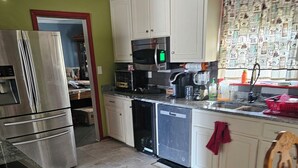 Una cocina con armarios blancos, un refrigerador de acero inoxidable, un microondas y un lavavajillas.