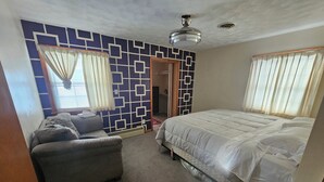 Un dormitorio con cama, sofá y pared decorada.