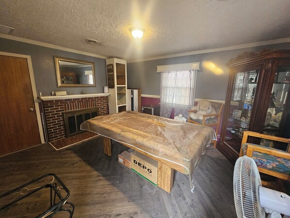 A room with a bed, a wooden cabinet, a mirror, a fireplace, and a window with curtains.