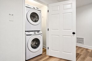 Una sala de bugaderia amb dues rentadores superposades i una porta blanca.